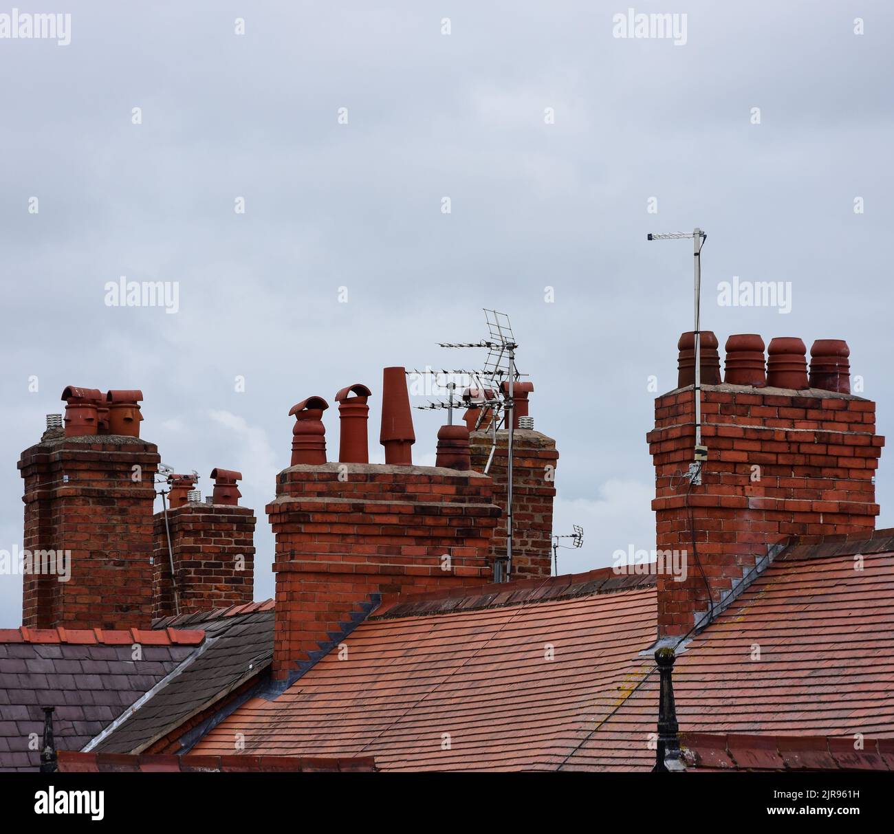 Clay chimney pots on the top of red brick chimney stack of a