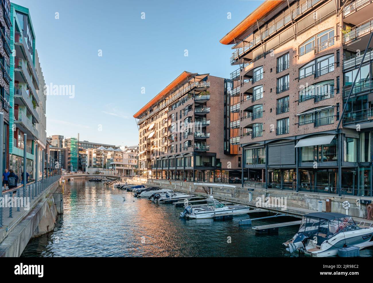 Oslo, Norway - August 13 2022: Evening view of the waterfront of Tjuvholmen, with boats and buildings facing the canal. Stock Photo
