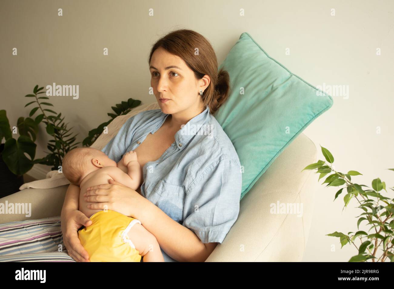 Mothed and baby at the chair. Breastfeeding in cradle position Stock Photo