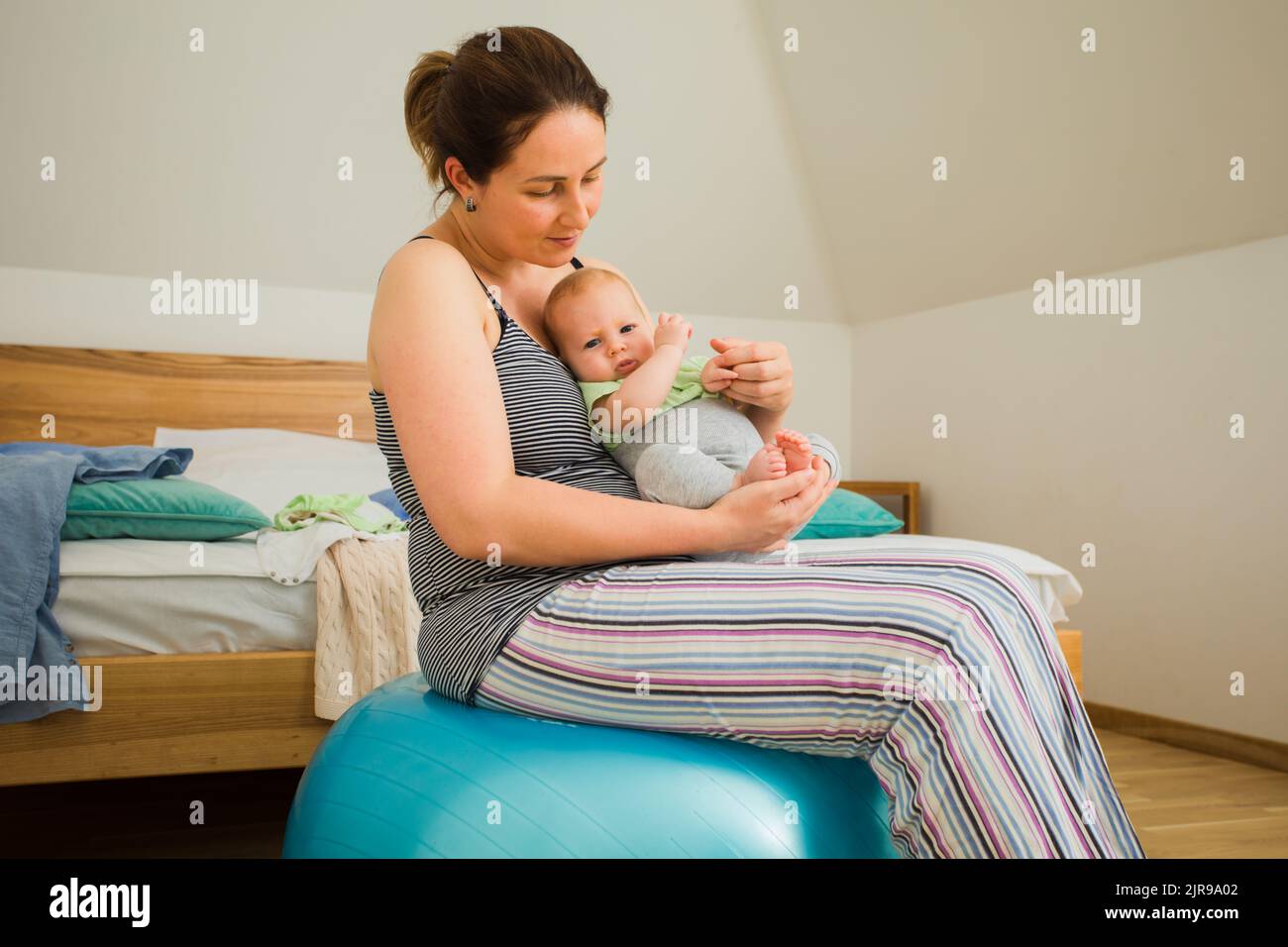 Mother holding and rocking baby sitting on fitball Stock Photo - Alamy