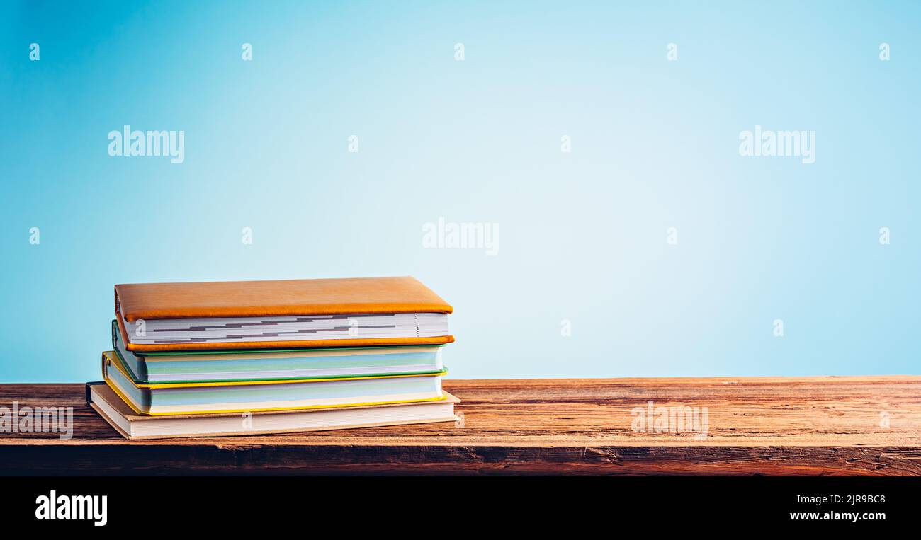 A stack of books and notebooks on desk or shelf. Education, studying and back to school concept Stock Photo