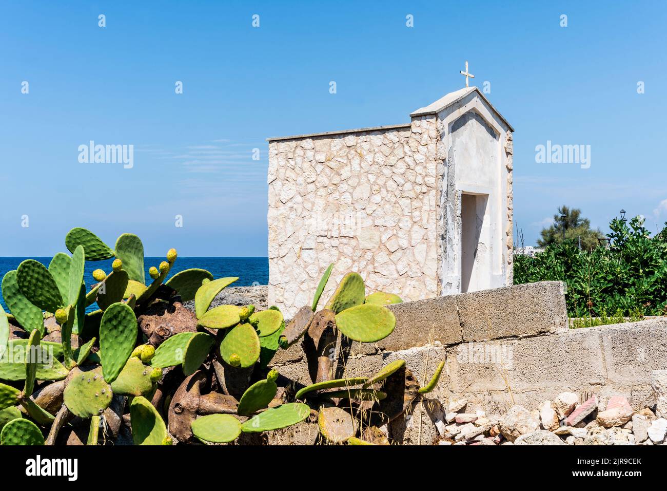 Catholic oratory along the rocky shore with prickly pears, in Mancaversa, marina of Taviano, Salento, Puglia, Southern Italy Stock Photo