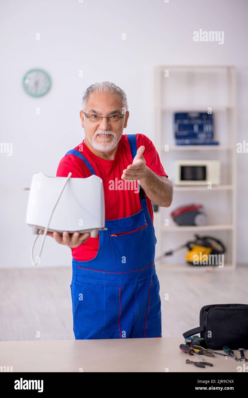 Old male repairman repairing toaster at Stock Photo Alamy