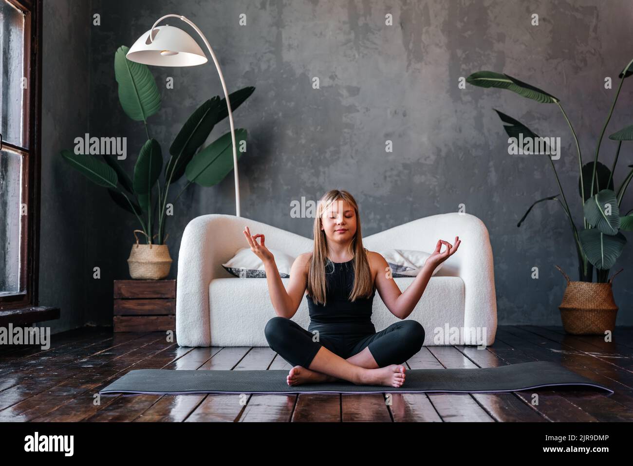 Young attractive girl practicing yoga, sitting in Half Lotus exercise