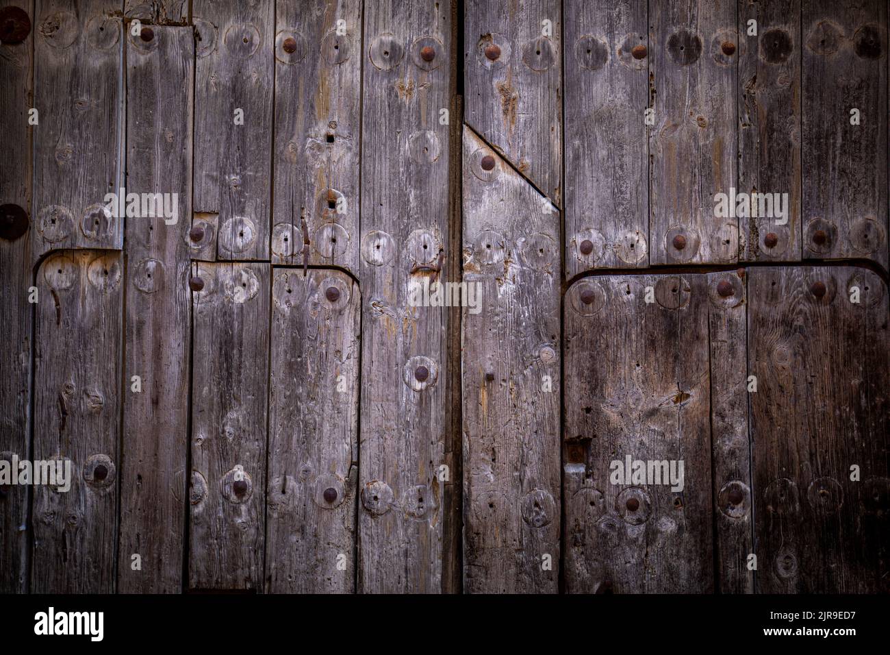 Antique weathered double leaf door with decorations on dark natural wood Stock Photo