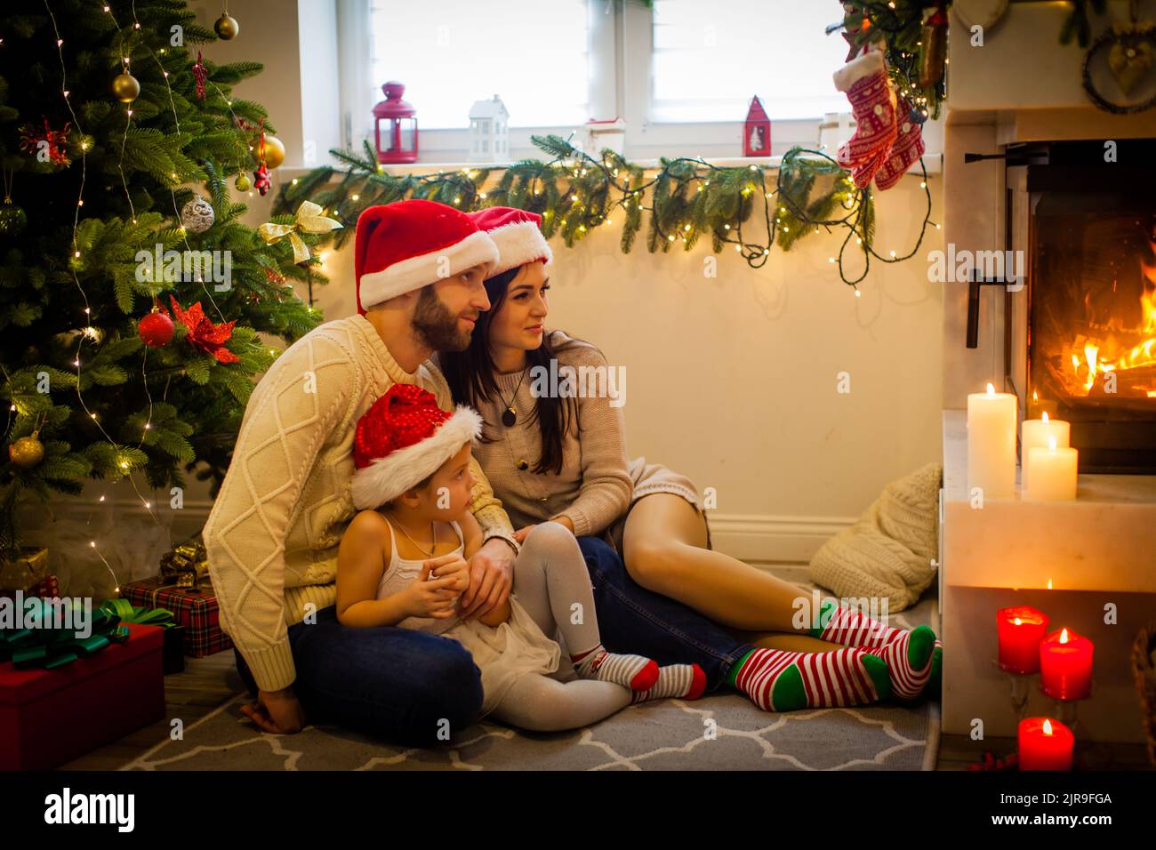 Happy family - parents and children sitting by fireplace on Christmas Eve Stock Photo
