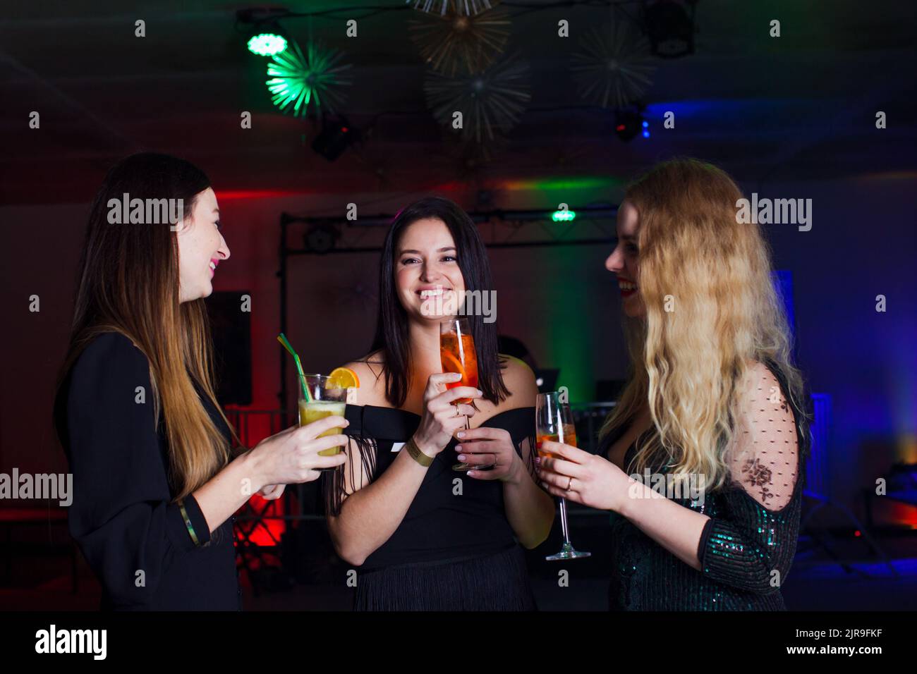 Women have fun and drinking cocktails with fruits in night club. Dance party Stock Photo