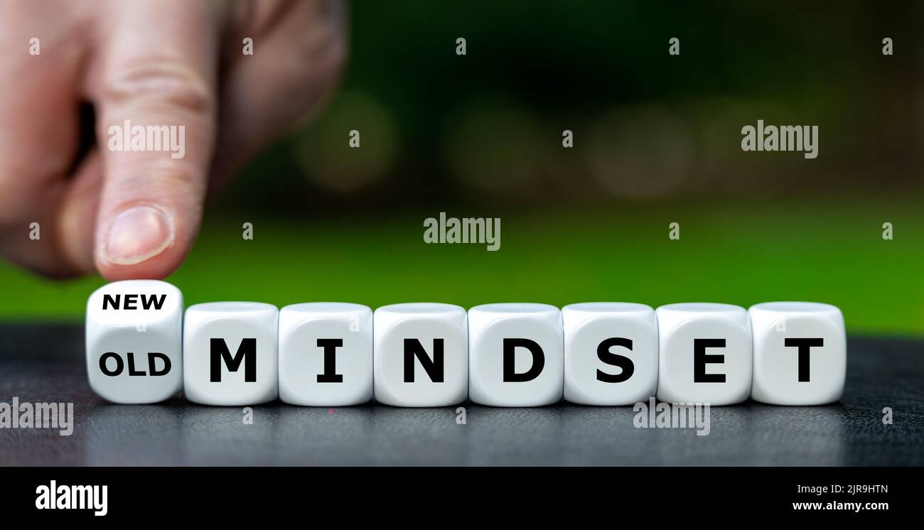 Hand turns dice and changes the expression 'old mindset' to 'new mindset'. Stock Photo