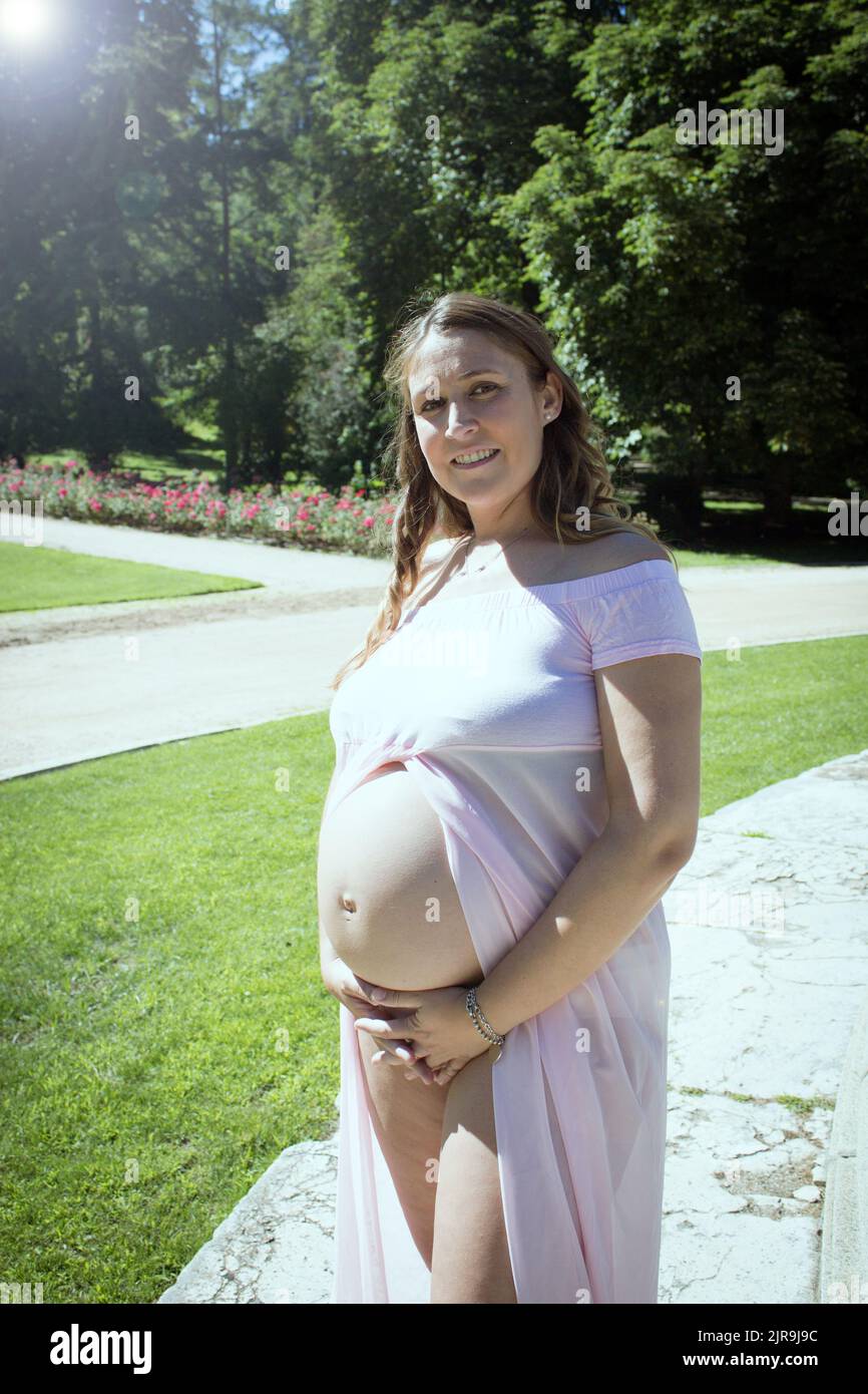 Seven Month Pregnant Woman In Pink Transparent Dress Holding Belly seven-month-pregnant-woman-in-pink-transparent-dress-holding-belly