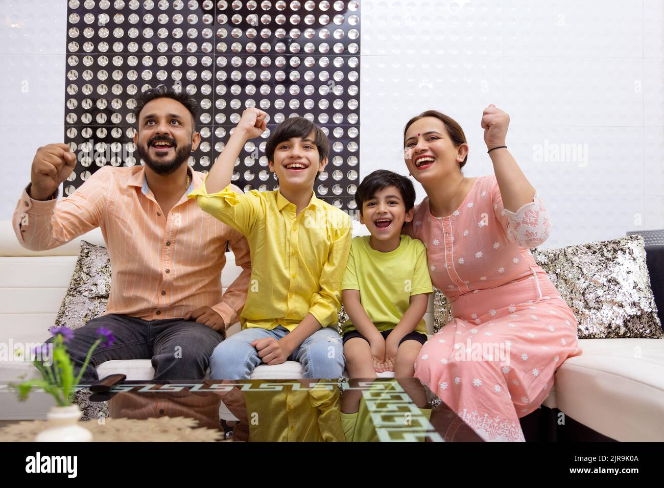 Family cheering together while watching TV in living room Stock Photo
