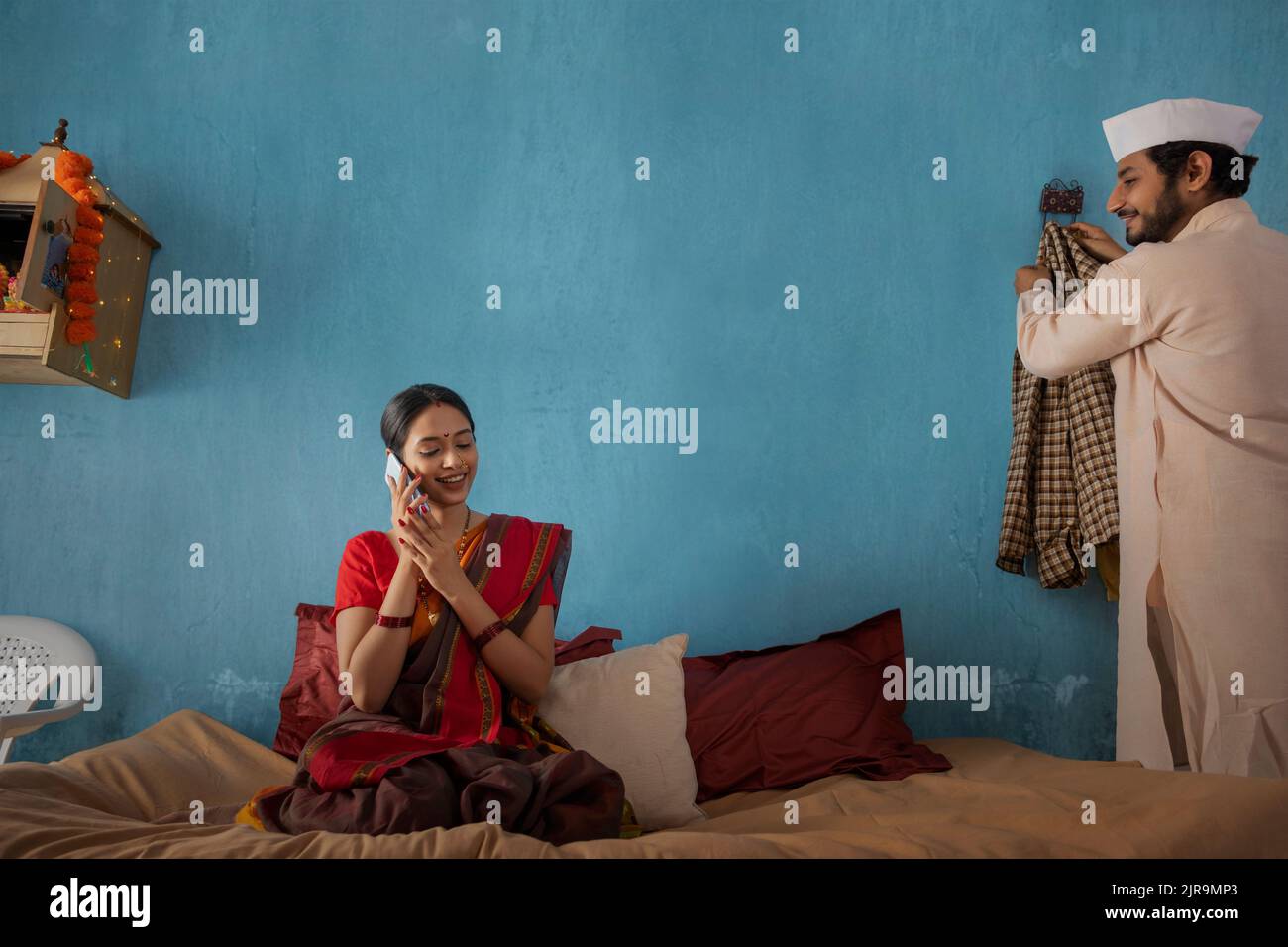 Maharashtrian woman talking on smartphone while her husband standing beside Stock Photo