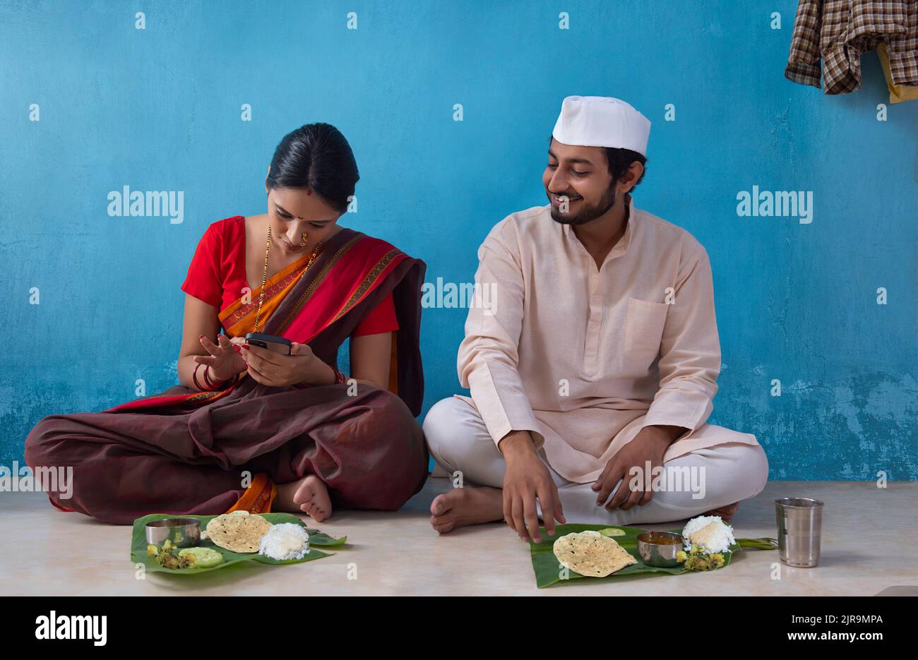Maharashtrian couple using smartphone during lunch time Stock Photo