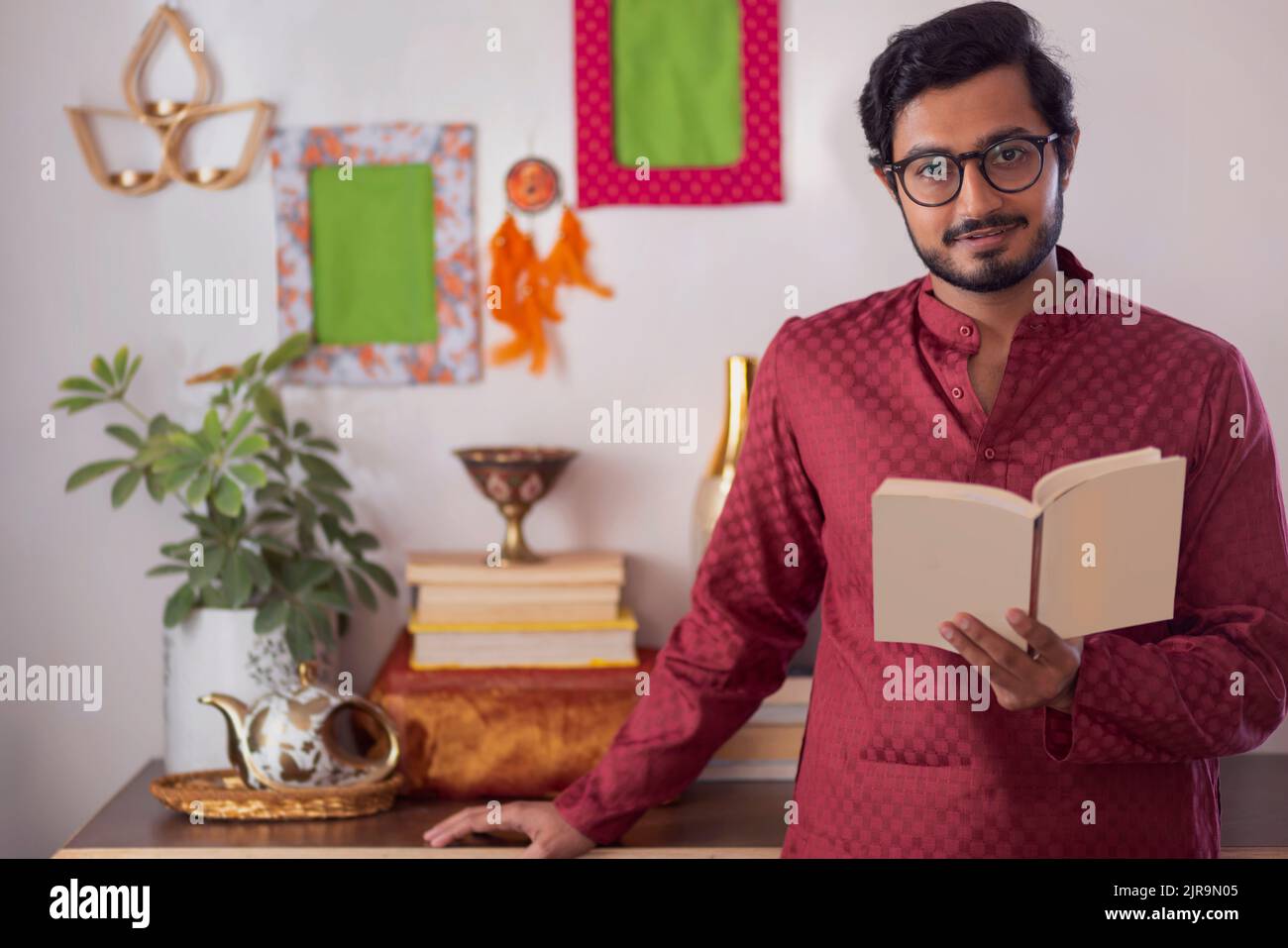 Portrait of a young man reading books in living room Stock Photo