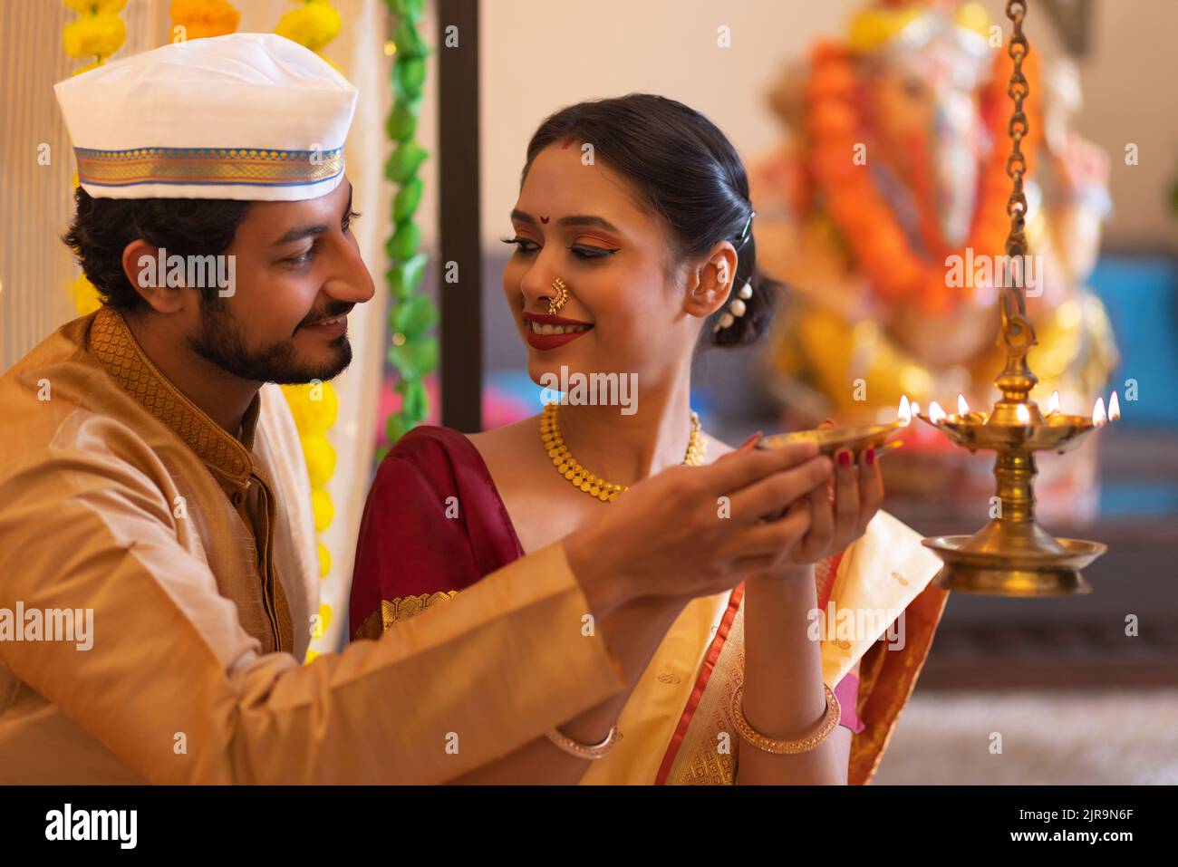 Maharashtrian couple lighting oil lamp on the occasion of Ganesh Chaturthi Stock Photo