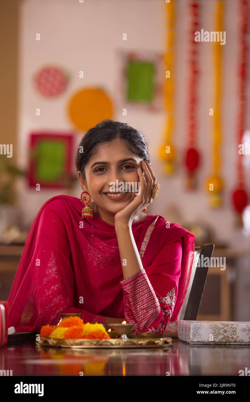 Portrait of cheerful woman sitting with a hand on cheek at home on the occasion of Raksha Bandhan Stock Photo