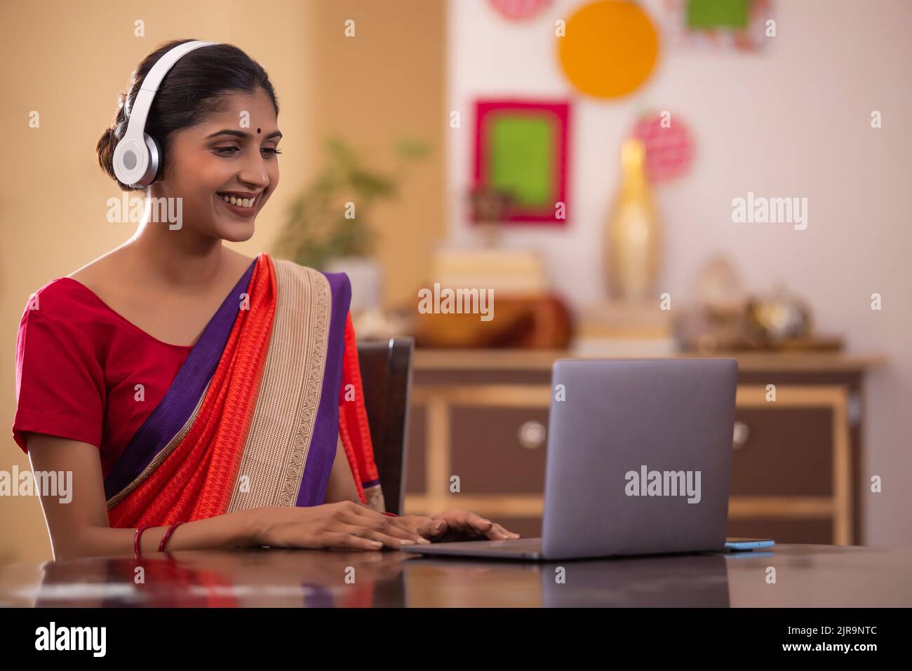 Smiling woman working on laptop at home Stock Photo