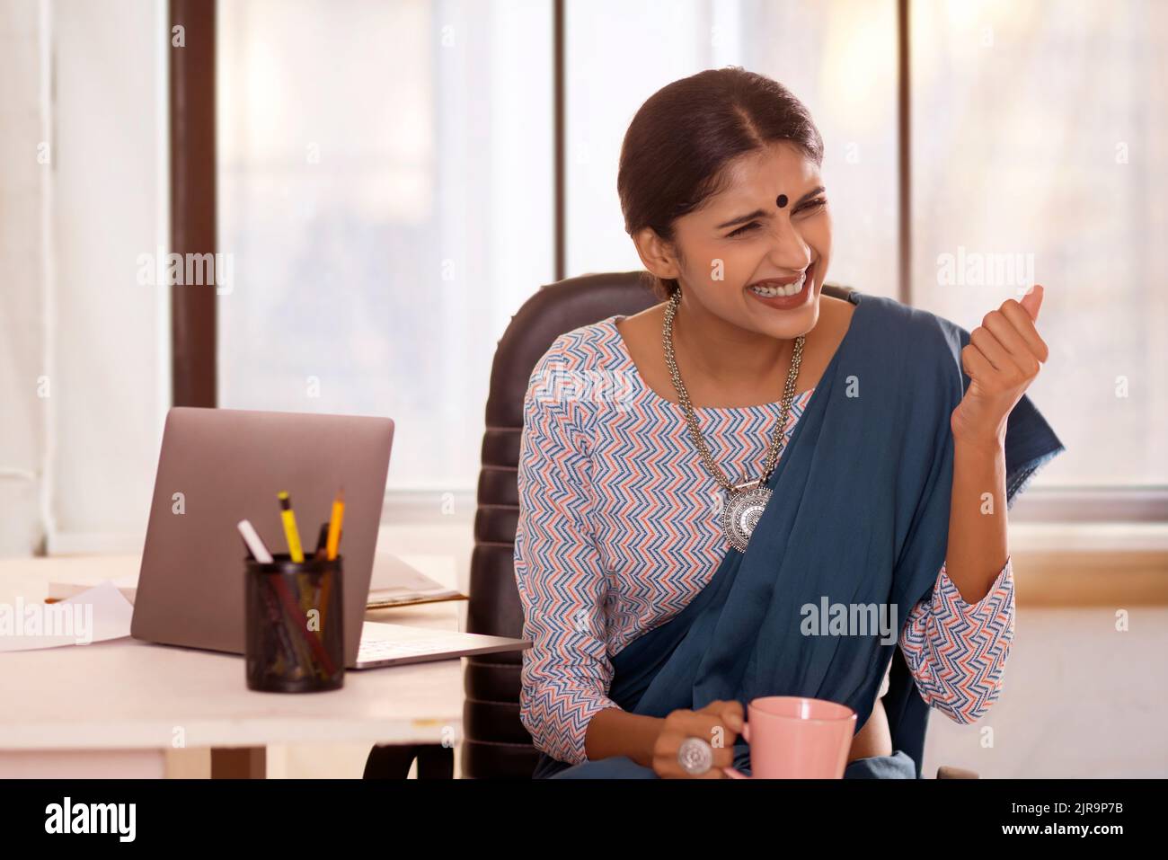 Portrait of happy woman cheering in office Stock Photo
