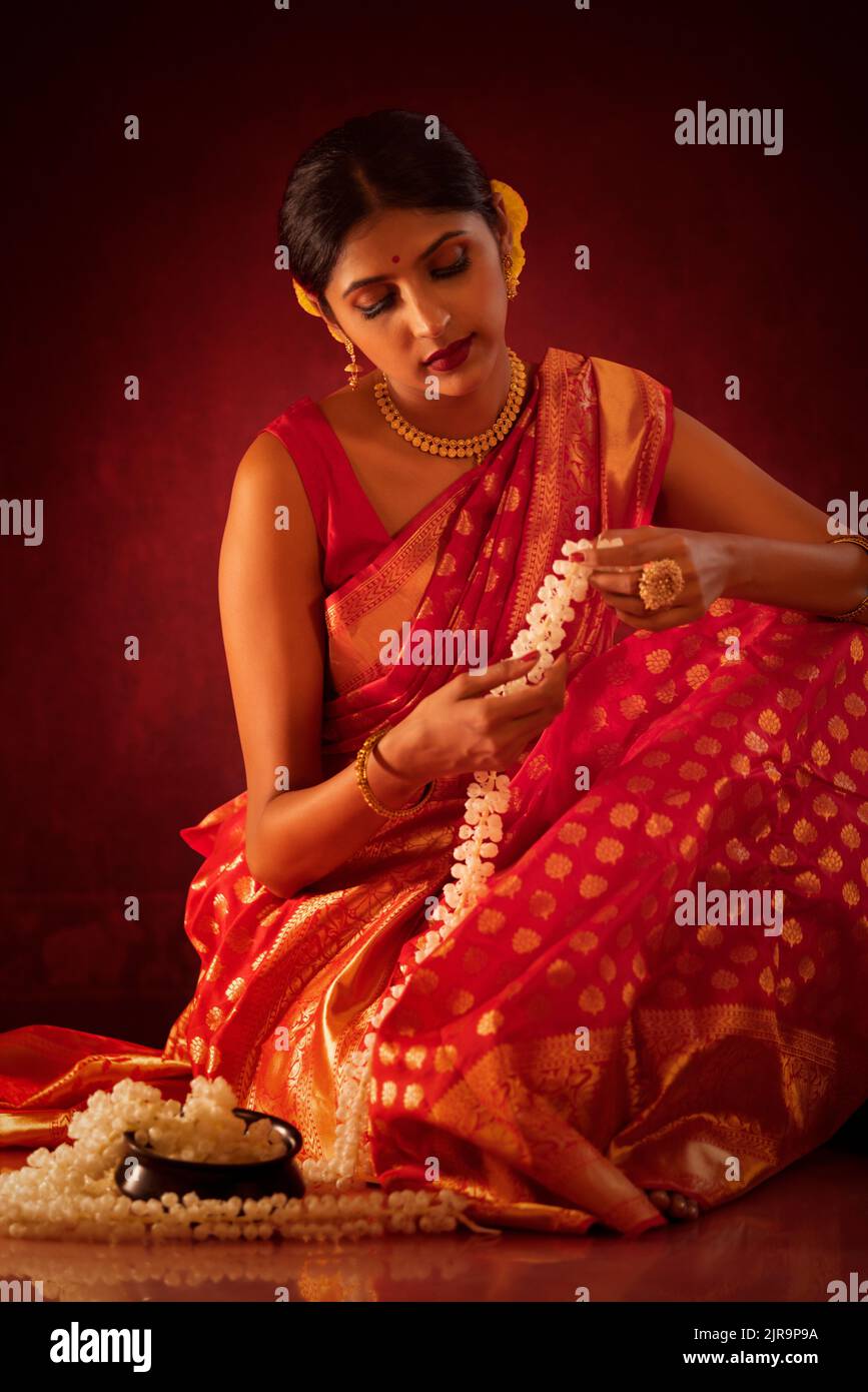 Portrait of Indian woman in traditional outfit against red background Stock Photo
