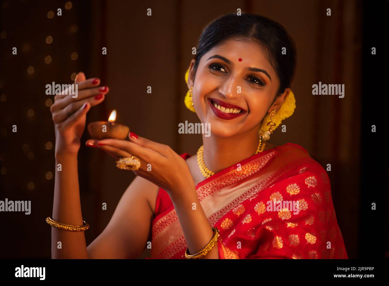 Close-up of a woman in red sari holding diya in her hand on the occasion of Diwali Stock Photo