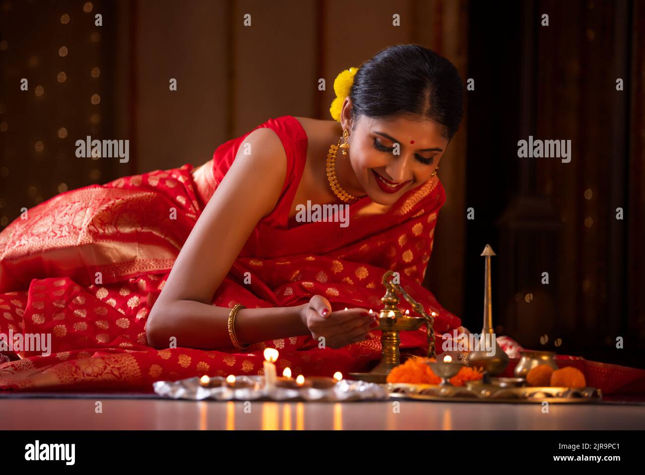 Woman in traditional outfit placing oil lamp at home on the occasion of Diwali Stock Photo