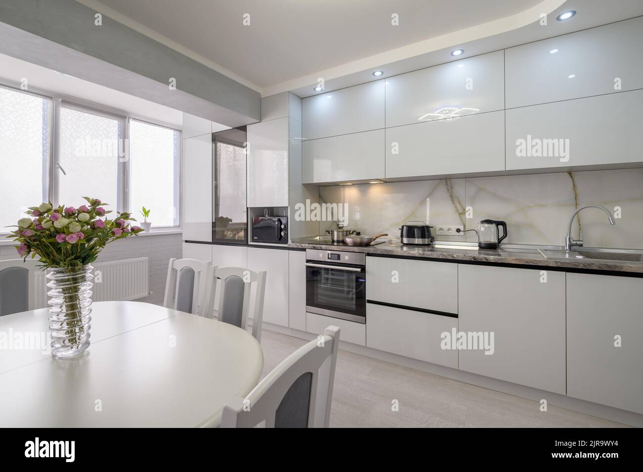 Interior of white modern kitchen with dining table Stock Photo - Alamy