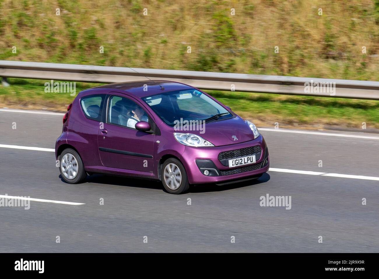 2012 Purple PEUGEOT 107 ACCESS 998cc petrol 5-speed small city car; travelling on the M6 Motorway UK Stock Photo