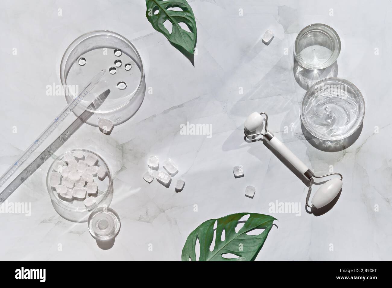 Home made moisturizer and white stone face rollers on off white marble