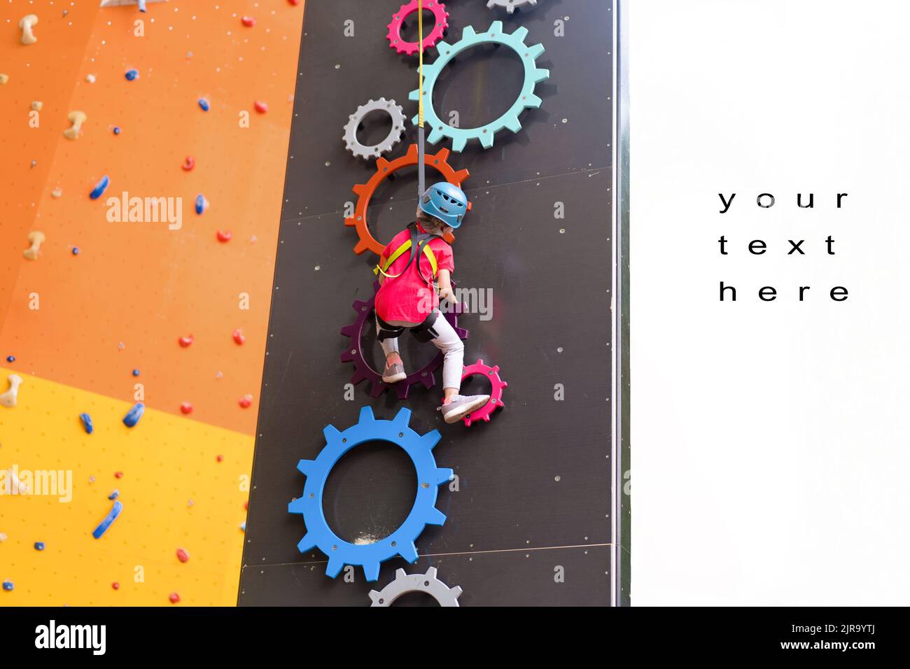 Child climbing on wall in amusement centre. Climbing training for