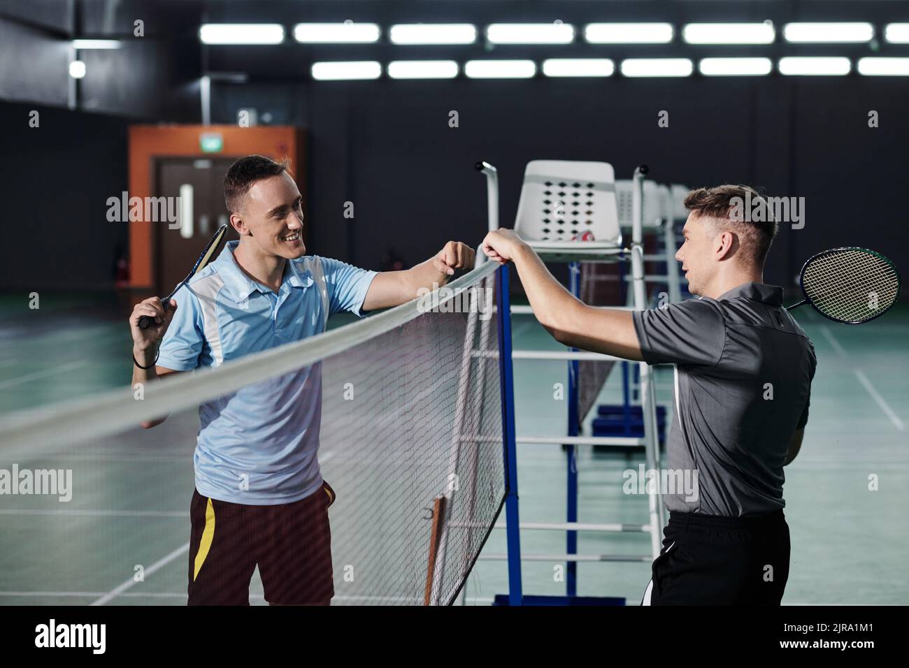 Excited badminton players making fist bump gesture before game Stock