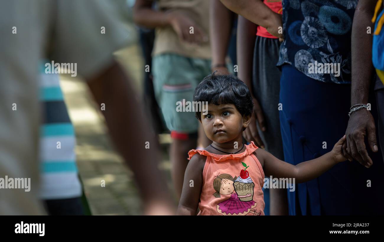 Child waiting to receive food parcel from a community almsgiving: Galle, Sri Lanka 30th July 2022 Stock Photo