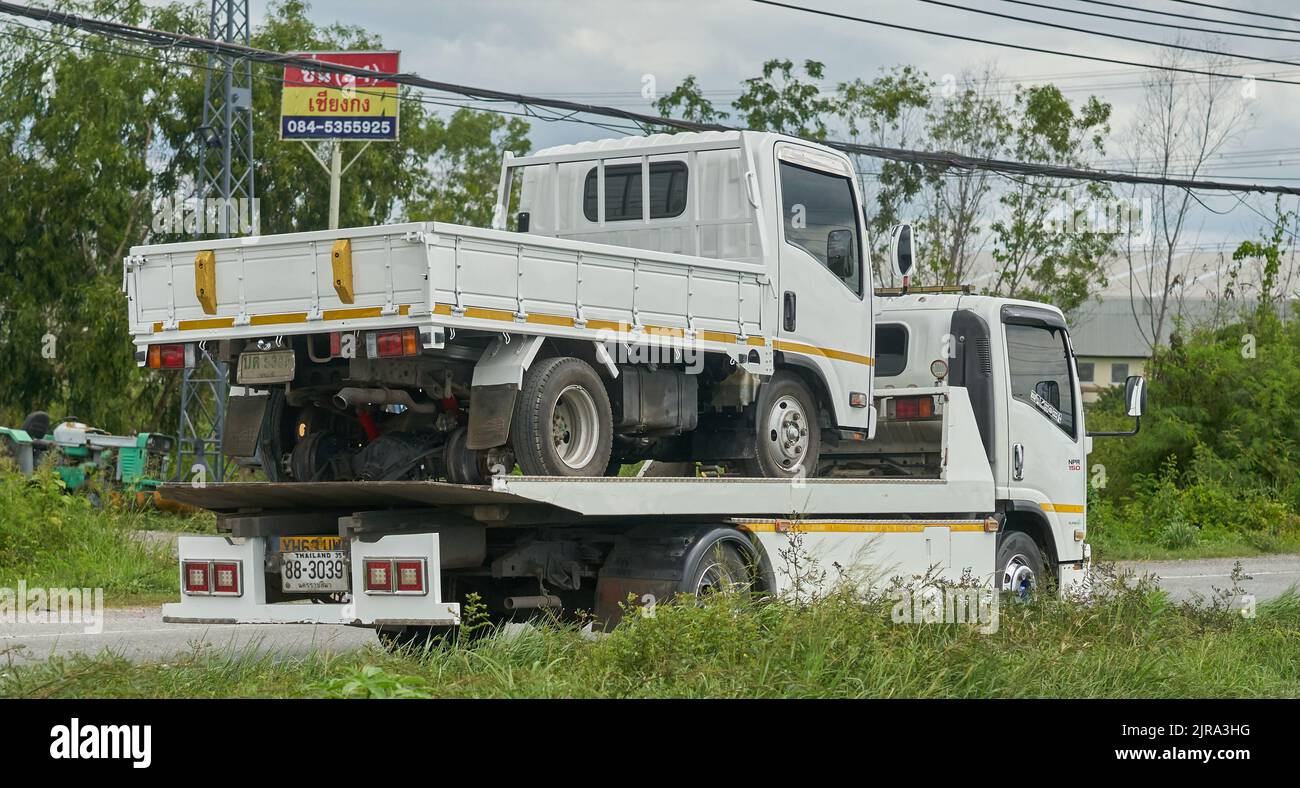 A small white truck being transported on a larger but similar looking tow truck, taken in Thailand. Stock Photo