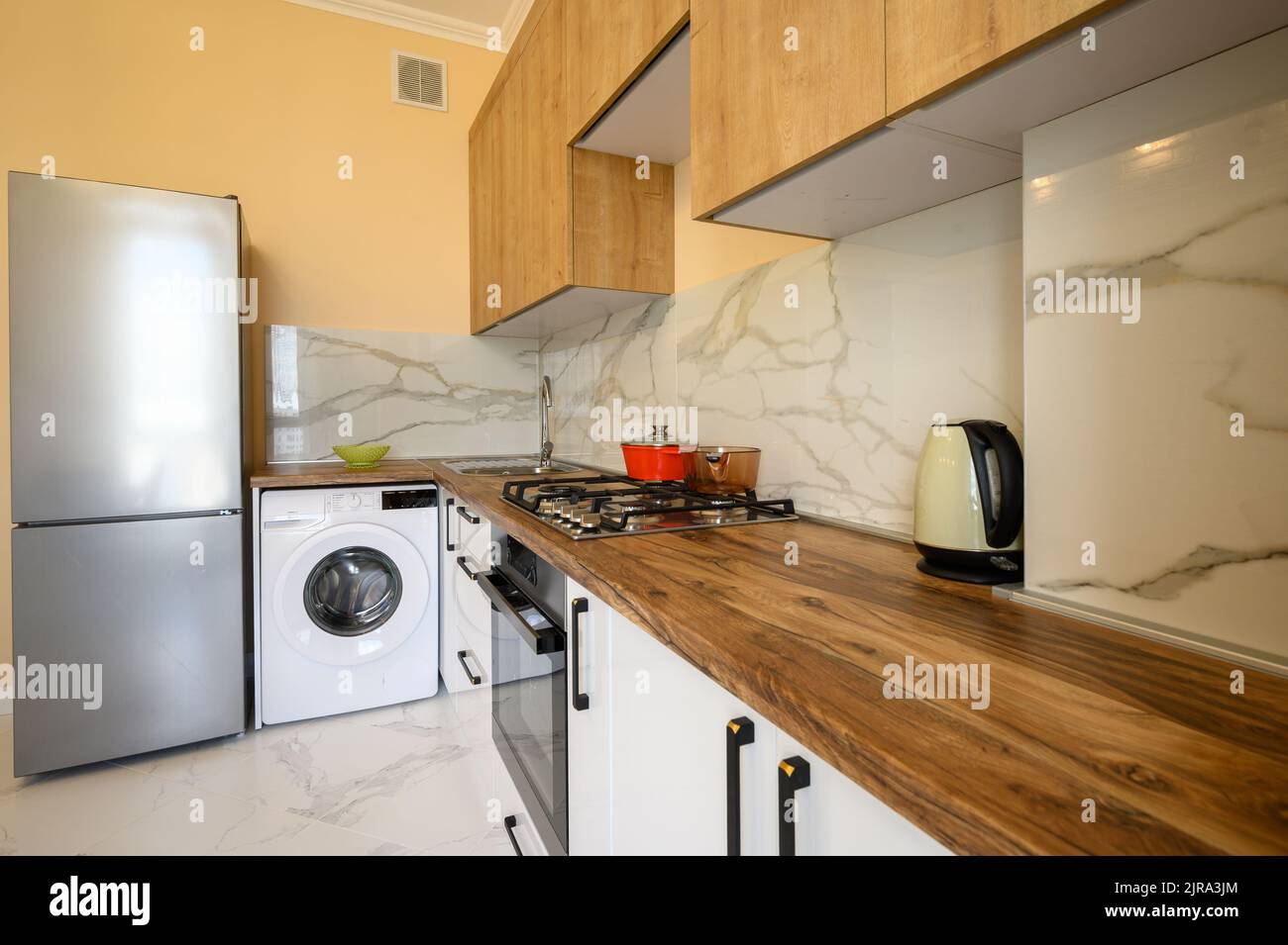 White and yellow wooden modern kitchen interior Stock Photo - Alamy