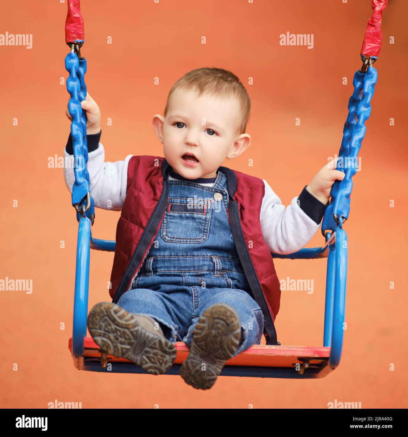 Sad toddler baby boy rides on a swing. A frightened child swings on the ...