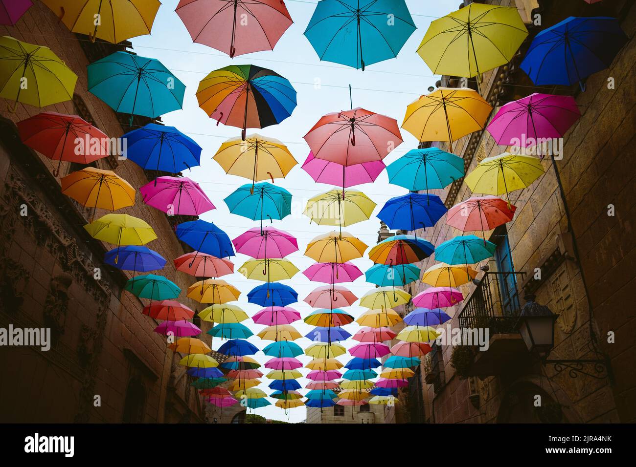 Colorful umbrellas hanging above city street.. Colorful umbrellas hanging in the sky used as street decoration. Stock Photo