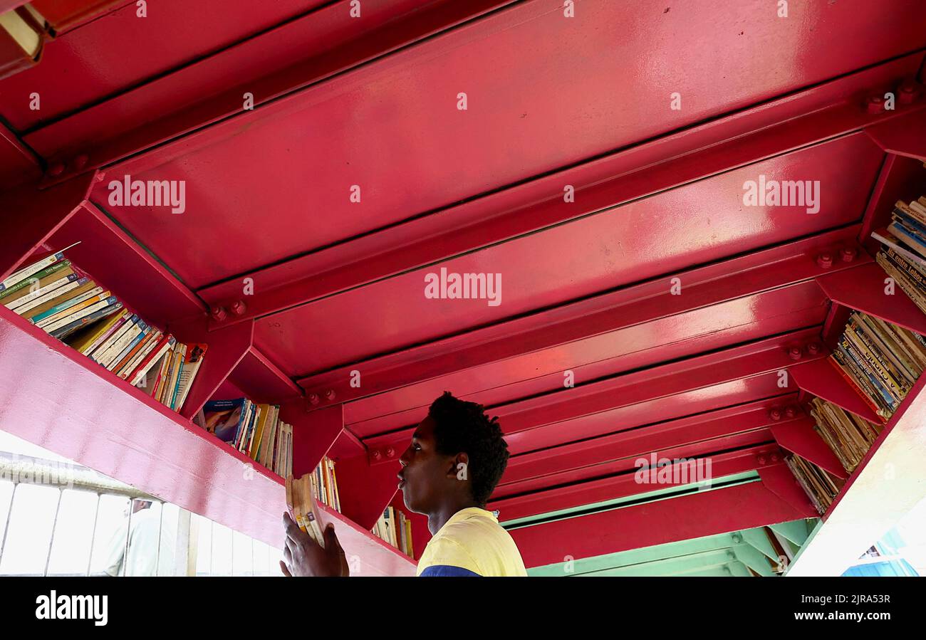 A man holds books at a makeshift 'library' under a bridge, at the Luanda surburbs in Angola, August 22, 2022. REUTERS/Siphiwe Sibeko Stock Photo