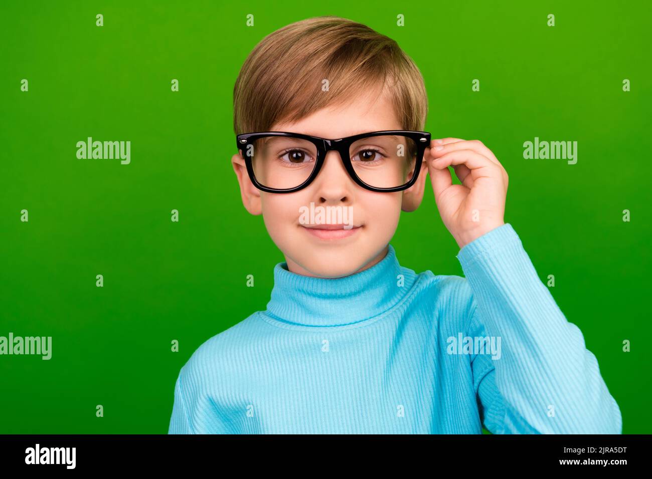 Photo of pretty charming little grandson dressed teal turtleneck hand eyewear smiling isolated green color background Stock Photo