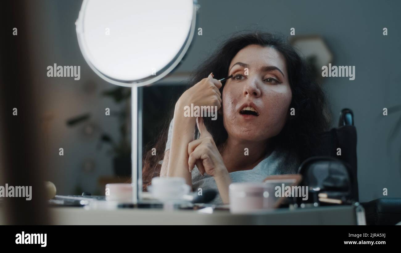 Woman with spinal muscular atrophy in a wheelchair applying eyeshadow