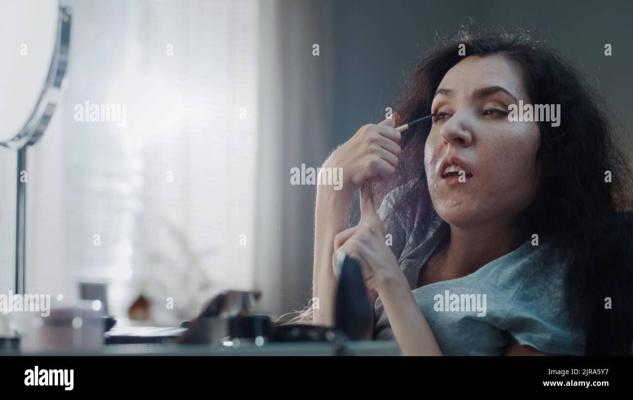 At home woman with disability in a wheelchair doing makeup at the table