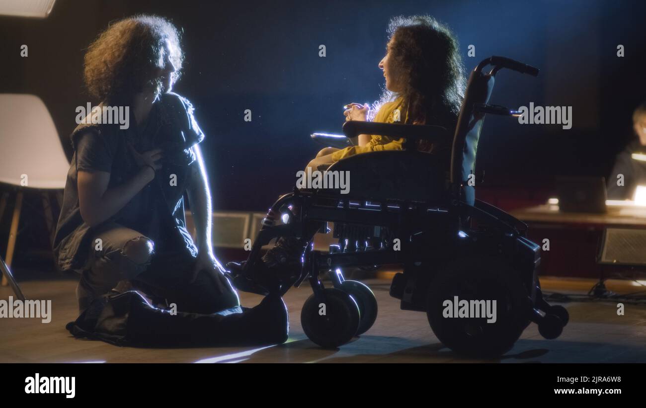 An actor kneeling next to a disabled actress in a wheelchair acting a