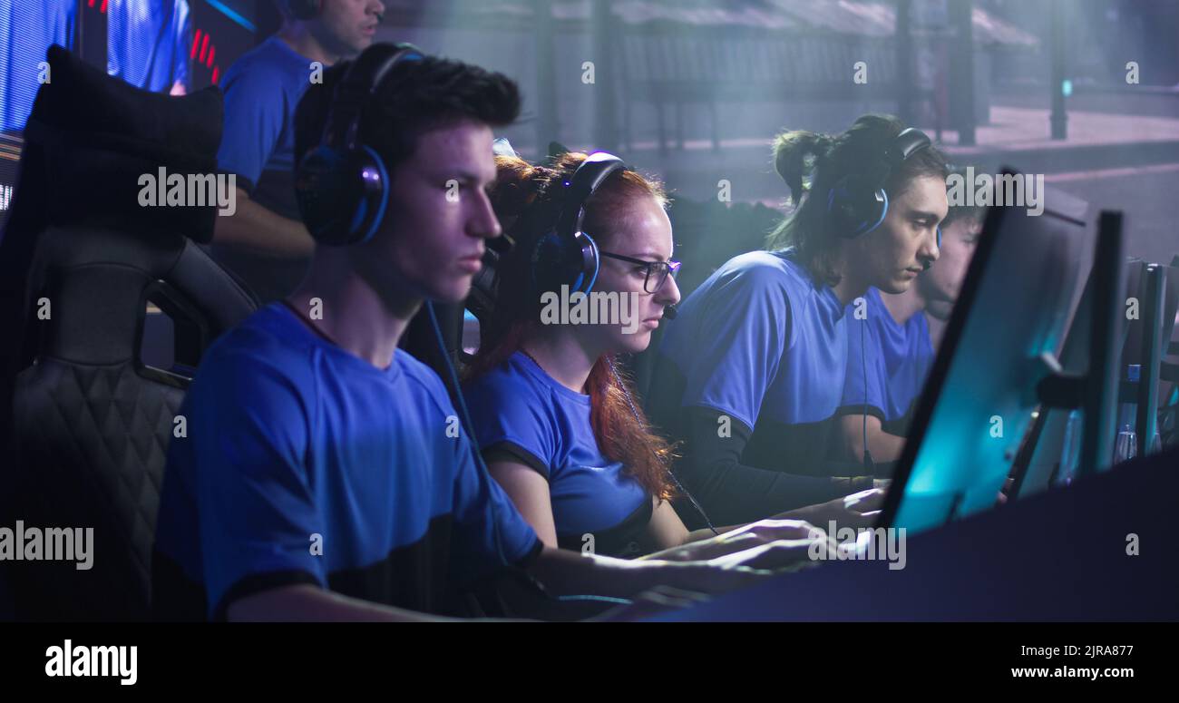 Team of male and female esportsman gamers playing shooter on computers ...