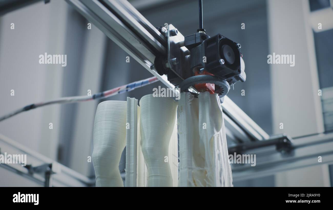 From below modern 3D printer printing legs of plastic statuette in workshop of modern creative design studio Stock Photo