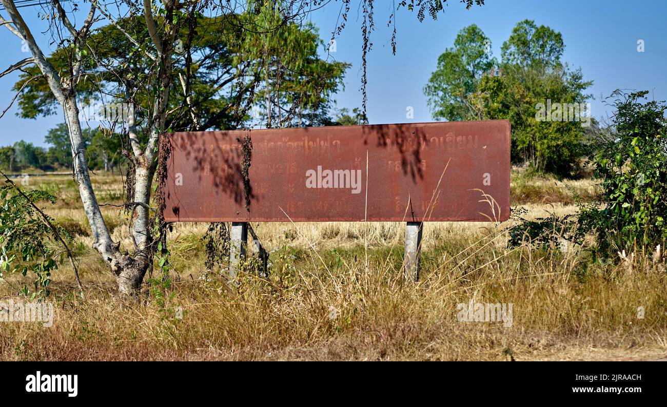 An old rusty metal Government information sign, by a roadside, taken in rural Thailand. Stock Photo