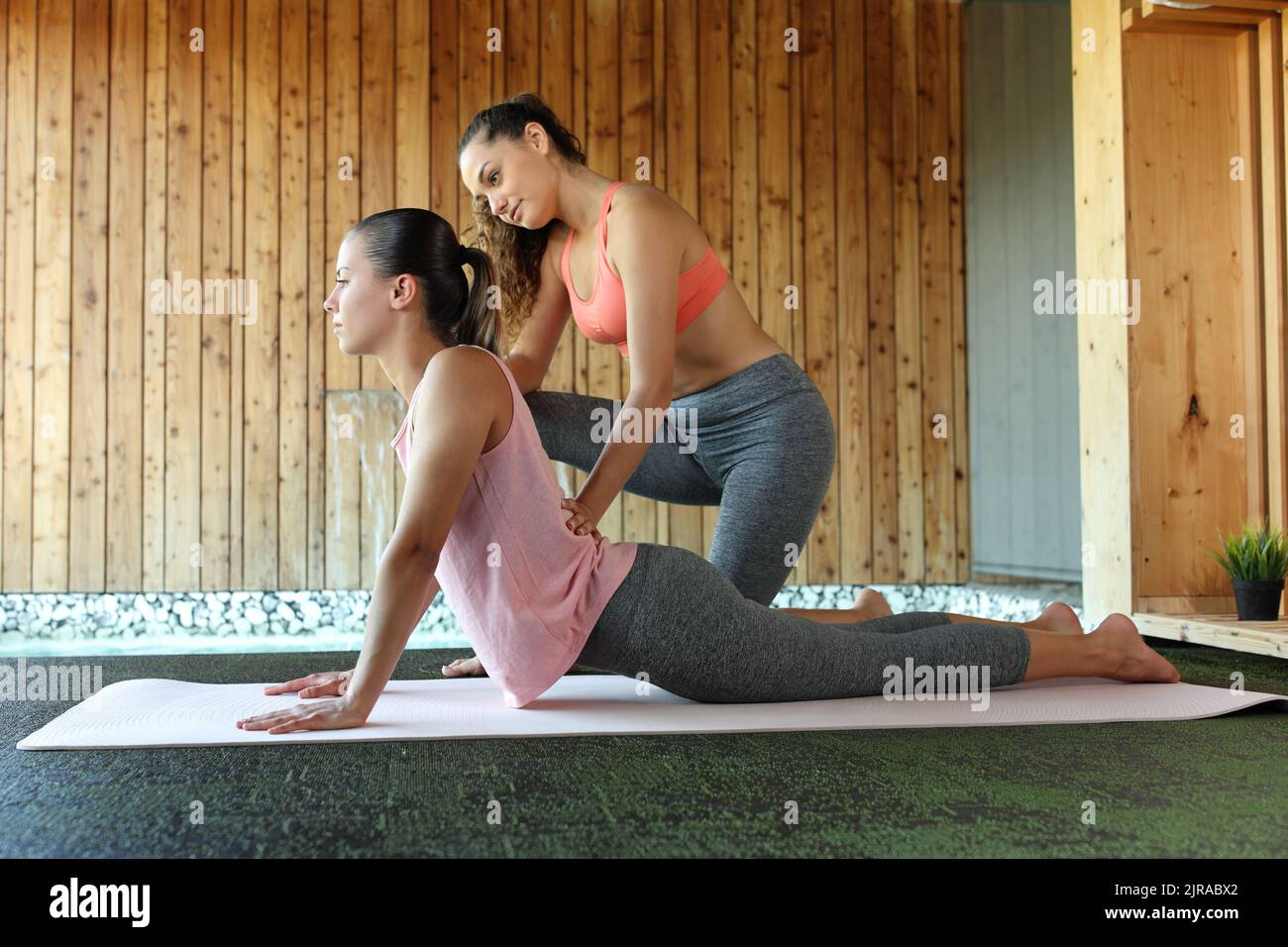Woman teaching yoga and student learning in spa interior Stock Photo
