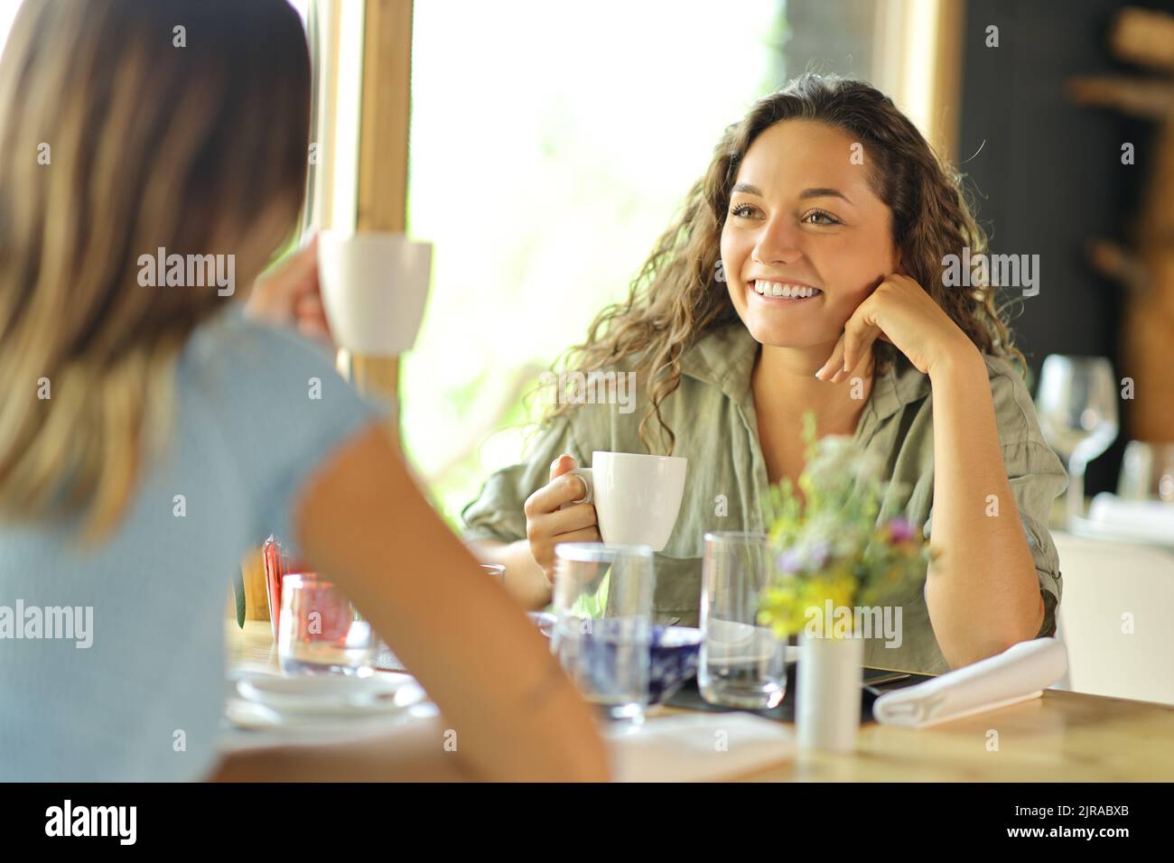 Two women talking and drinking coffee sitting in a restaurant Stock Photo
