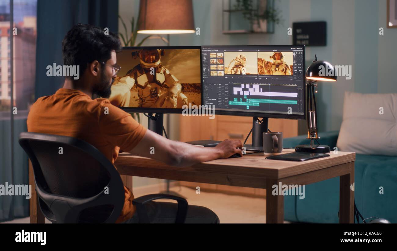 Back view of male content creator using computer to edit cosmonaut ...