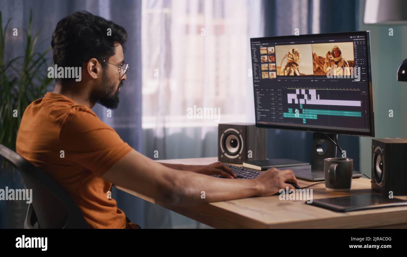 Back view of male content creator using computer to edit cosmonaut ...