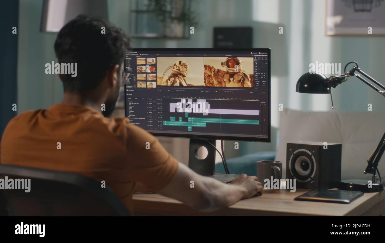 Back view of male content creator using computer to edit cosmonaut ...