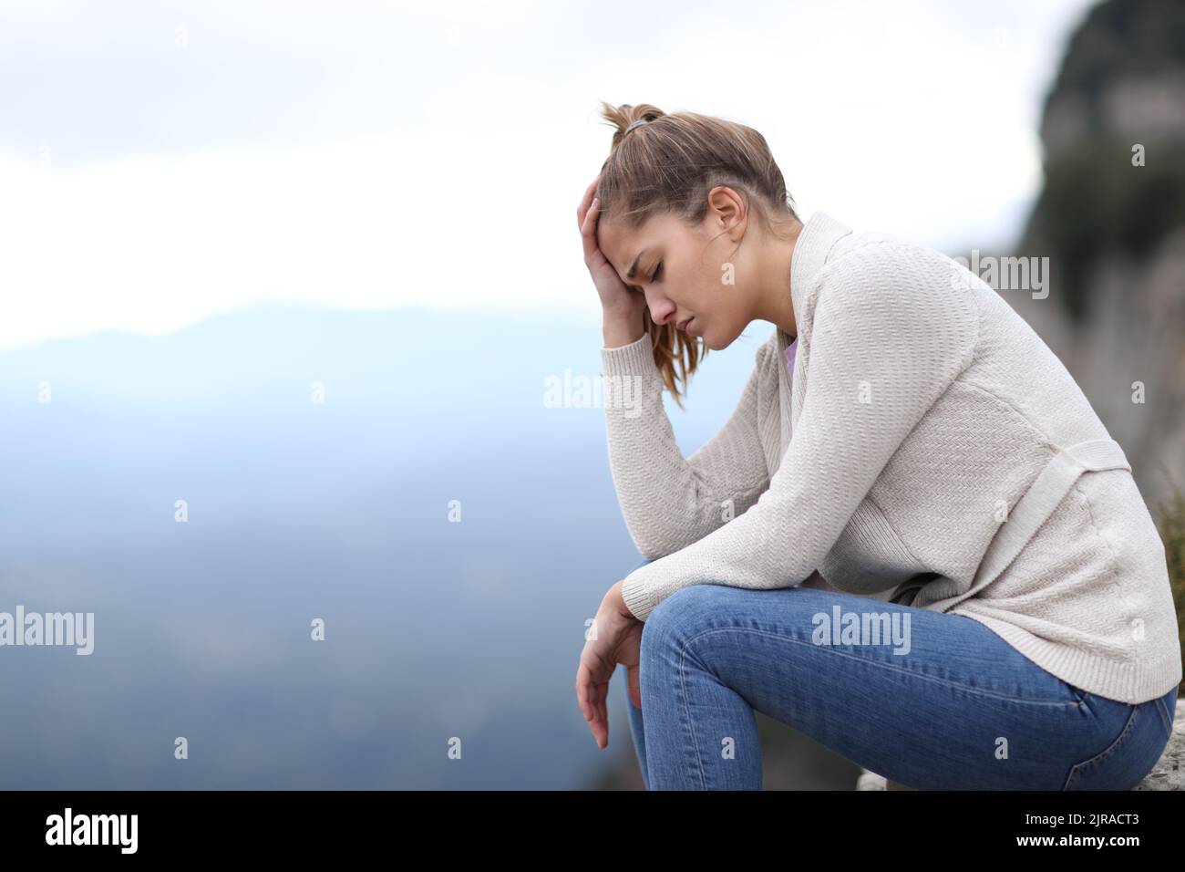 Side view portrait of a sad woman complaining alone in the mountain Stock Photo
