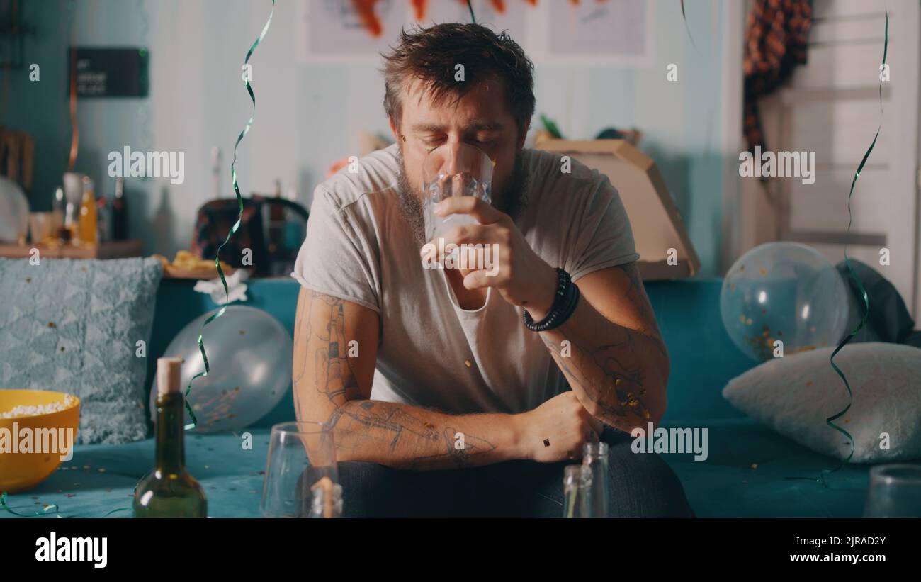 Drunk bearded male dropping effervescent aspirin pill into glass of