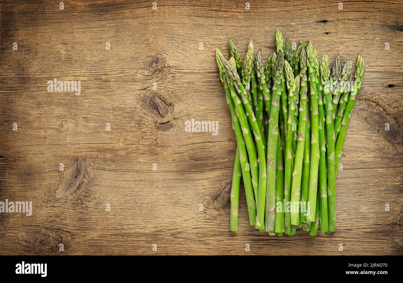 Green asparagus heap on wooden background. Copy space Stock Photo